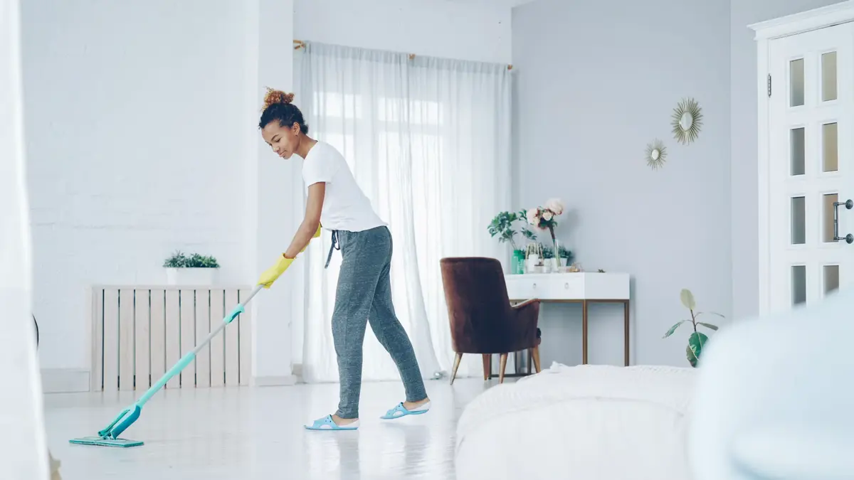 Person mopping the floor of a bright, clean living room